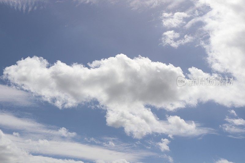 蓝色天空映衬着蓬松、缕缕白云的特写