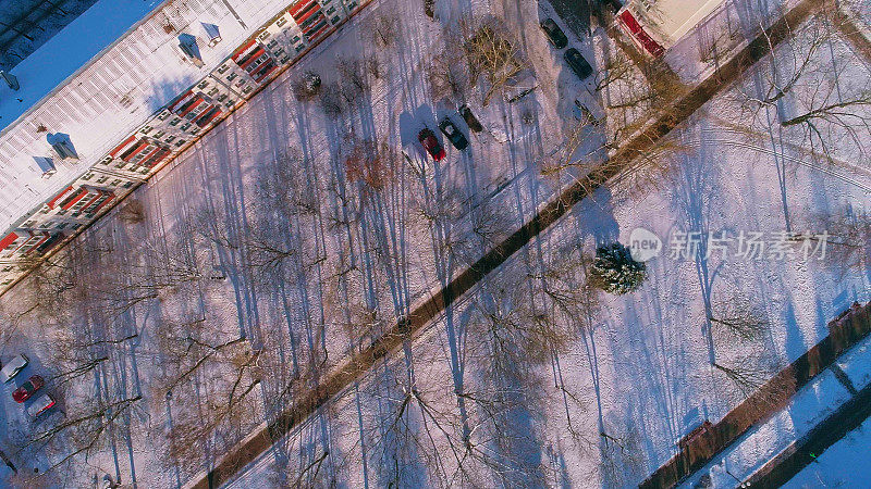 俯视图，正上方鸟瞰被雪覆盖的冬季城市住宅区。滑动和旋转复杂的摄像机运动