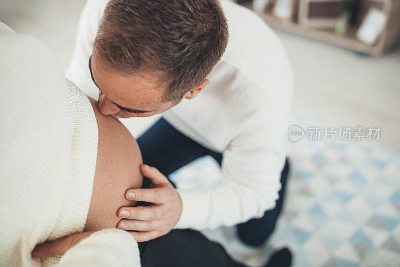 丈夫通过女人的肚子亲吻新生儿