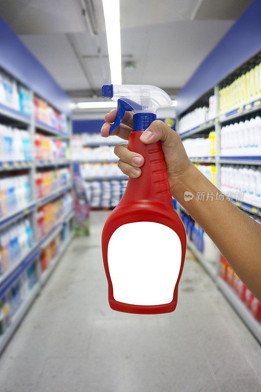 一只手拿着红色的装有洗涤剂的喷瓶
