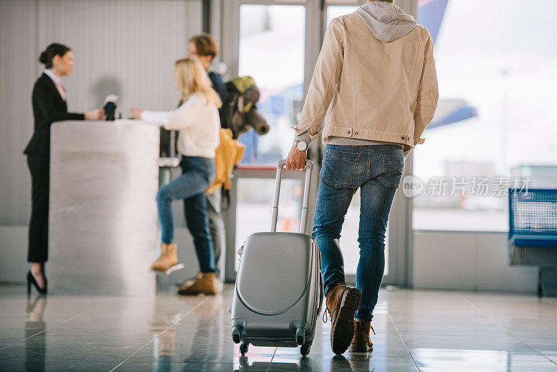 一名男子拿着行李箱前往机场办理登机手续