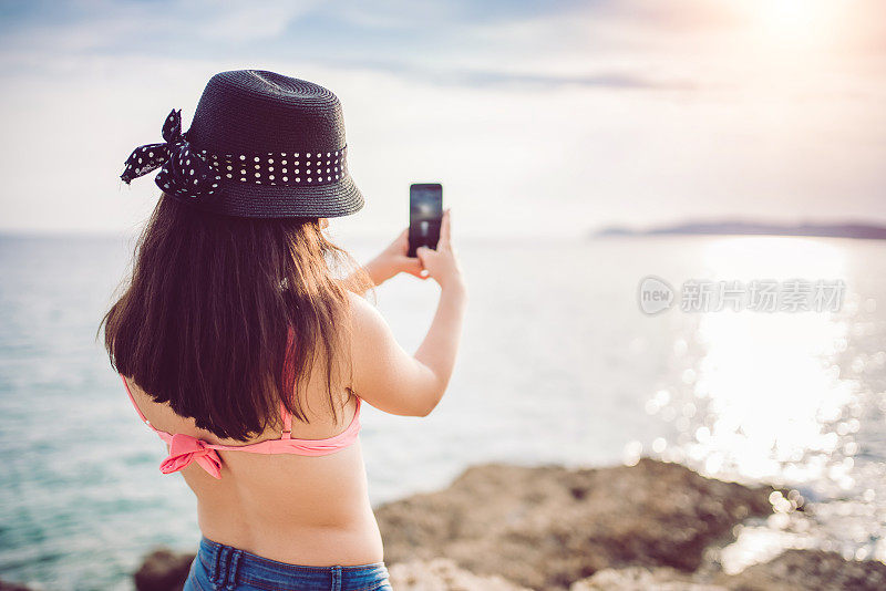 年轻女子在海上拍摄日落
