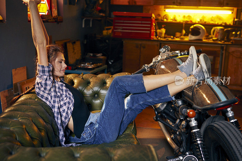 时尚的老式摩托车车库。下班后放松的女人