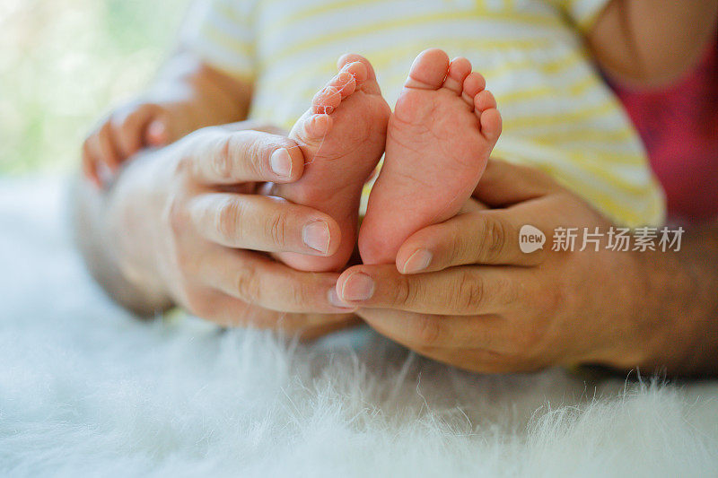 脚上九个月大的女婴在妈妈手中