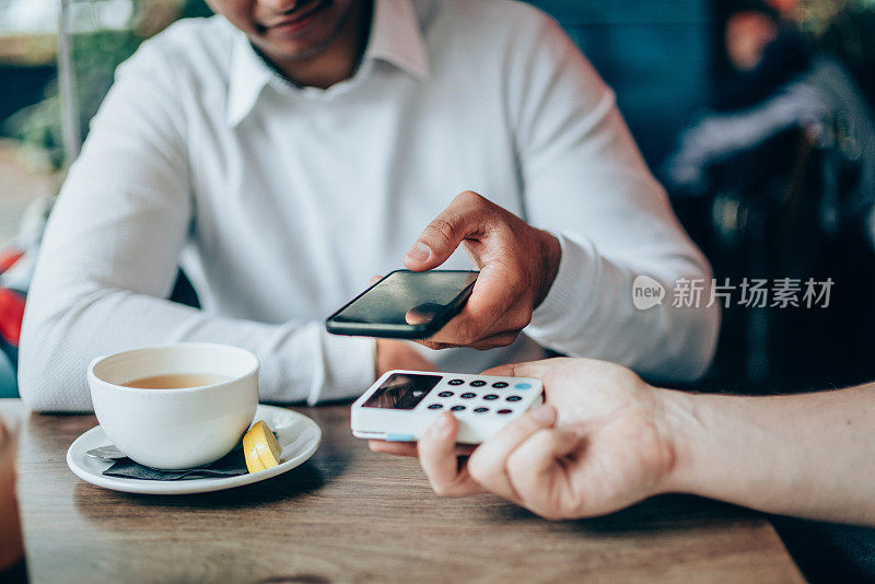 一名男子在咖啡馆用智能手机非接触式支付
