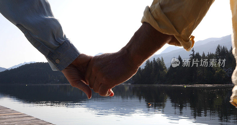 日出时分，男人和女人手拉手走在湖上的码头上