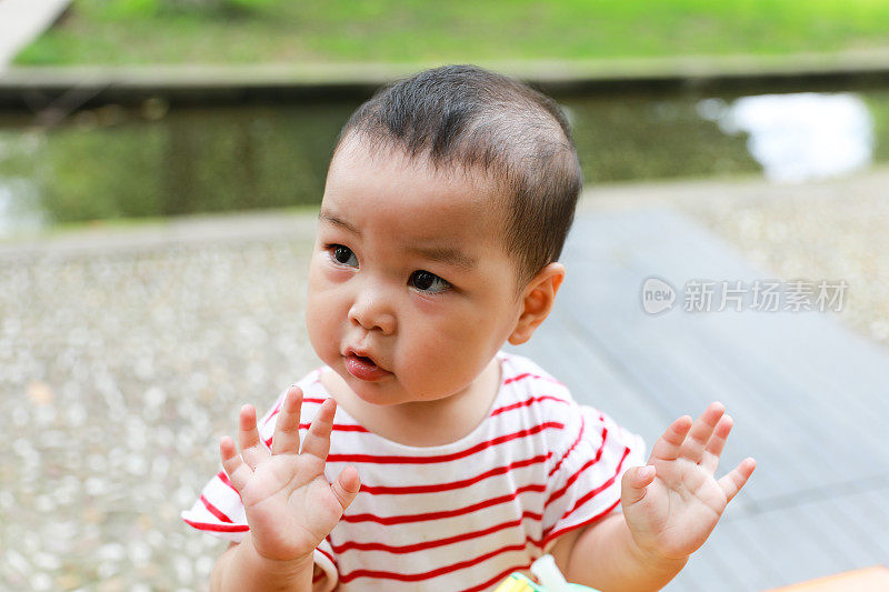 这是一个中国小女孩的特写镜头，她一边看着自己的右侧，一边把手举在空中