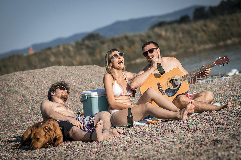 一群快乐的年轻人一起坐在海滩上