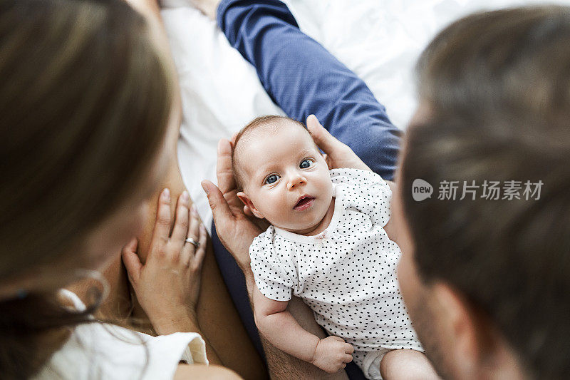 妈妈，爸爸和婴儿在白色的床上玩