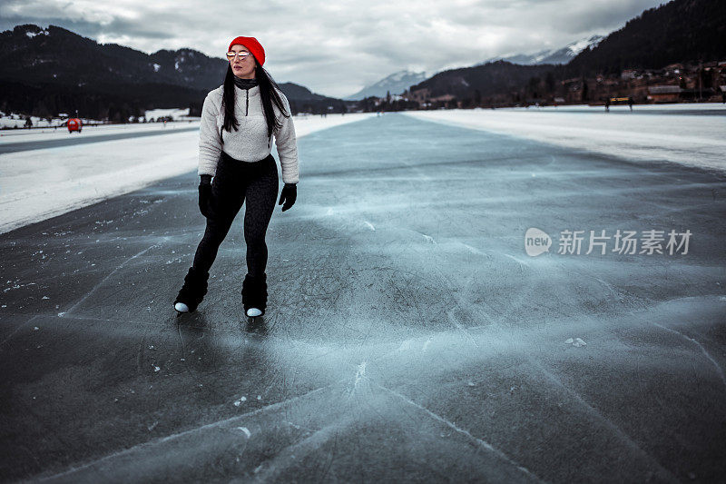 一位女滑冰运动员站在结冰的湖面上