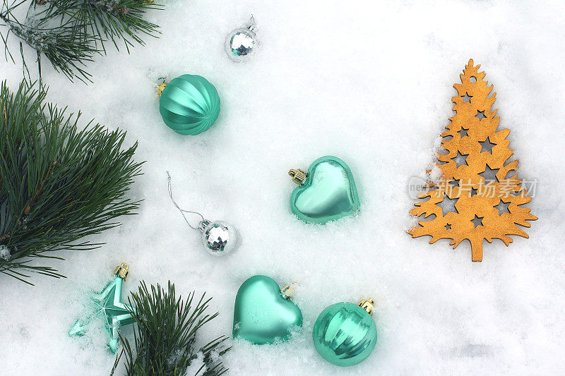 圣诞玩具躺在雪地里。银色装饰，绿松石和金色。俯视图，平放