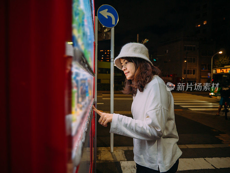 亚洲女人选择一些饮料在自动售货机