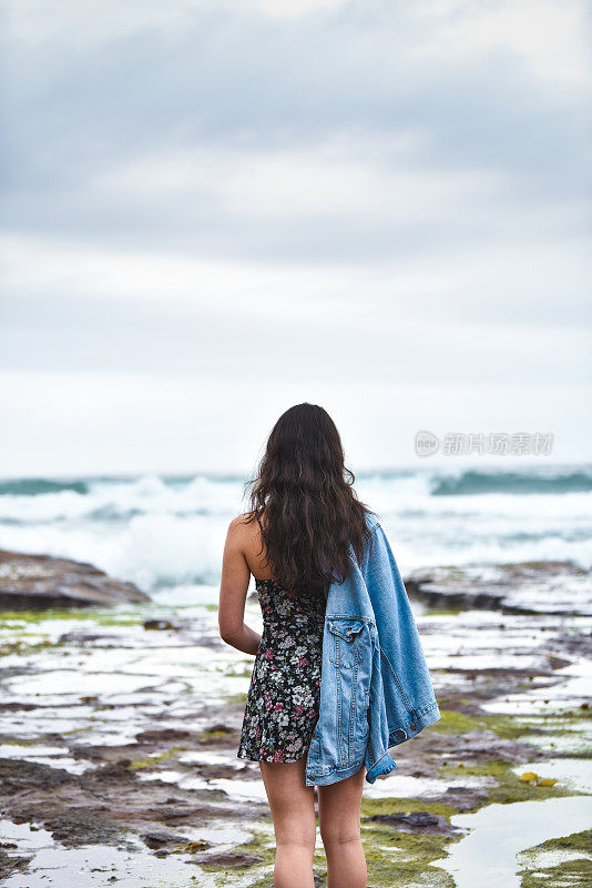 在一个沉闷的日子里，退潮时走向大海的年轻女子