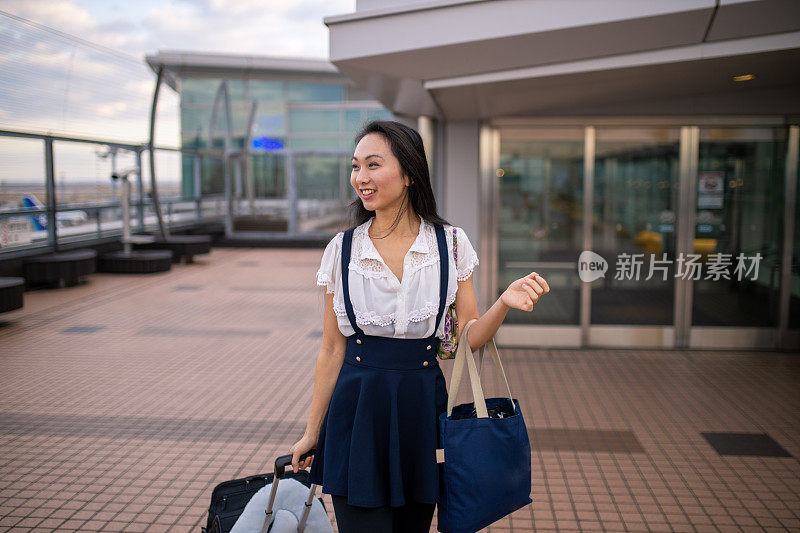 年轻的亚洲女子走在机场观景台上