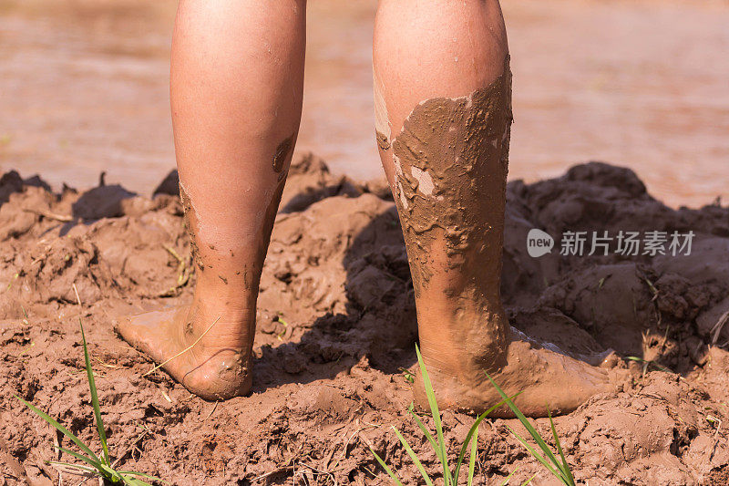 光着脚在泥里，男孩的腿在泥泞的水坑里玩耍后