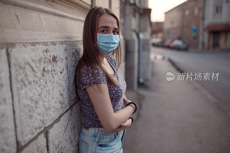 美丽的年轻女子戴着防护面具在街上