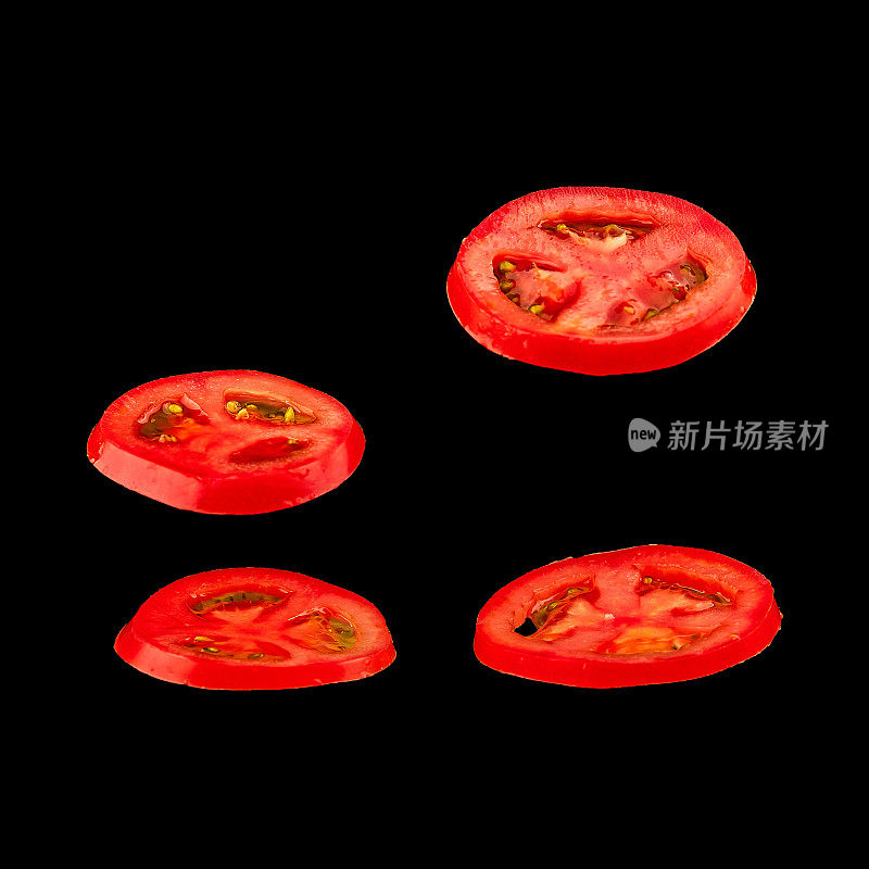 飞行的番茄。切片红番茄孤立在黑色背景。轻浮的蔬菜漂浮在空中。