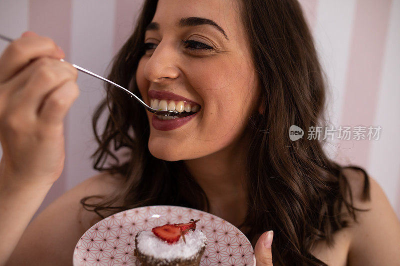 一个美丽的年轻女子微笑着吃着健康的甜食