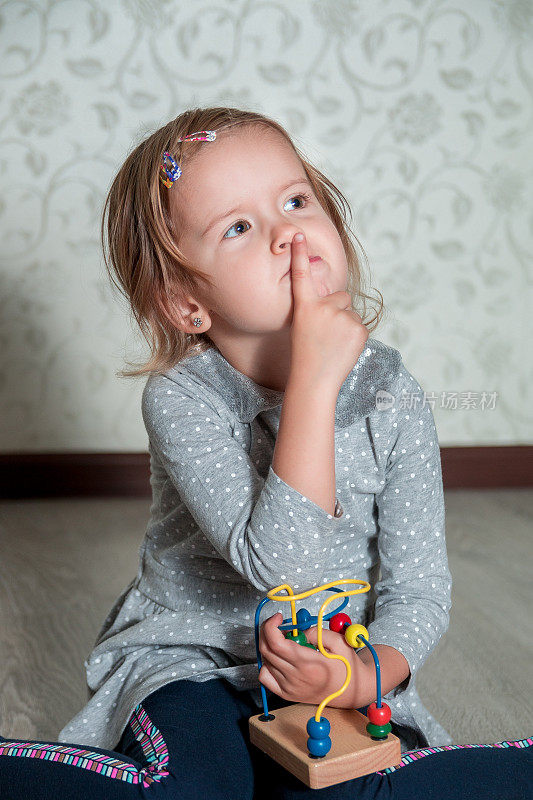 孩子在玩迷宫。小女孩把手指放在嘴边思考。教育玩具。