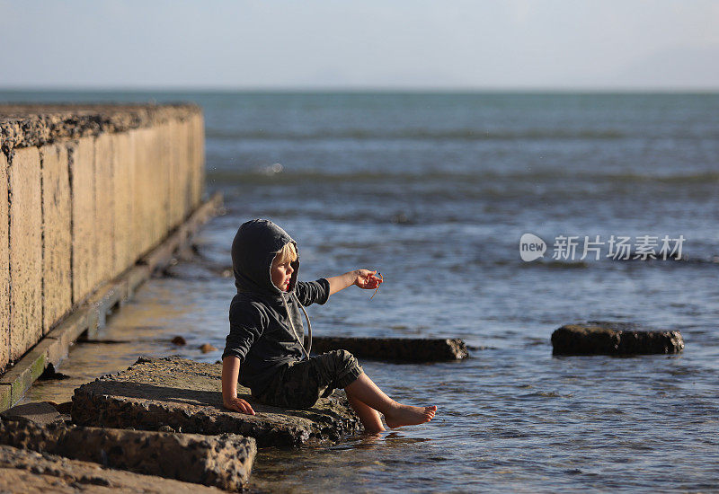 一个小男孩在海滩上玩耍，寻找贝壳。