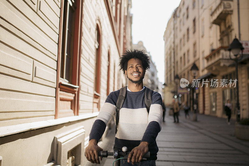 一个快乐的年轻非裔美国人骑着他的电动车去上班