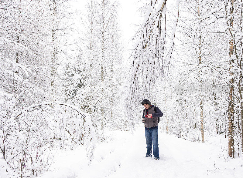 白种人在冬天的雪地里。那个人正在休息和喝咖啡。步行旅游。