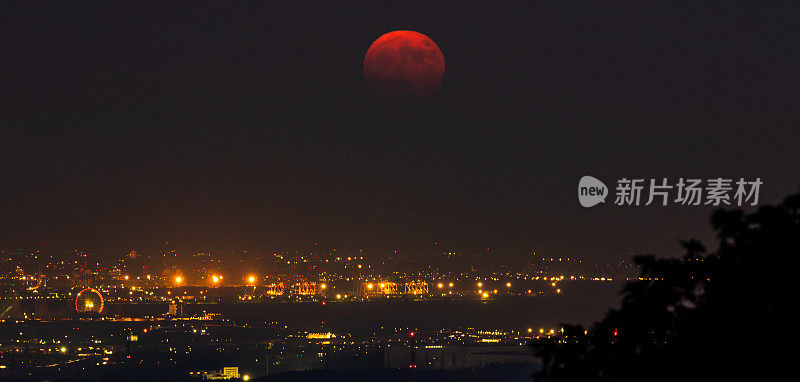 一轮深红的满月升起在城市上空