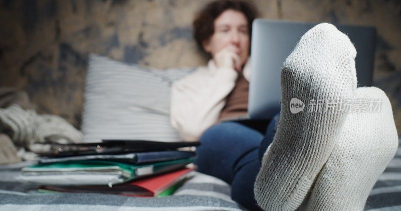 成熟的女人在家工作。注重脚上穿的羊毛手工袜子
