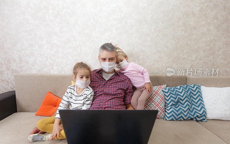 一位年轻的父亲和他的孩子们在家里用一台自我隔离的笔记本电脑工作。全职的概念。Freelance.Telecommuting。