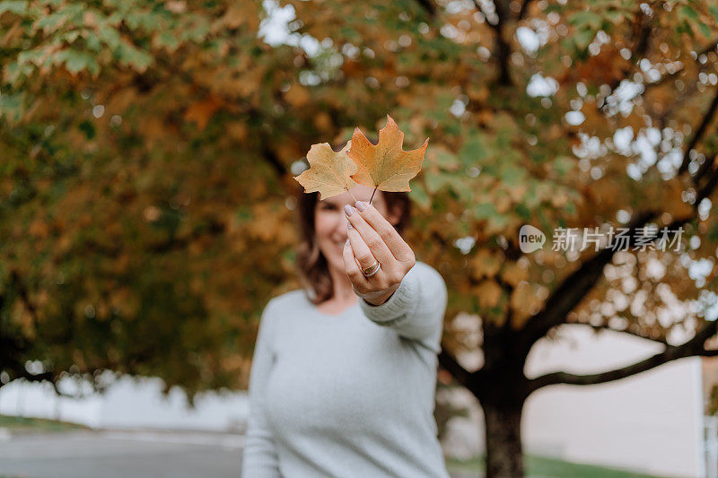 一个拉丁妇女在秋天拿着枫叶