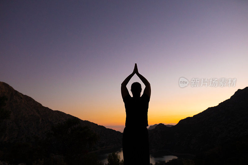 成熟的女人在马略卡岛的风景中练习瑜伽和正念