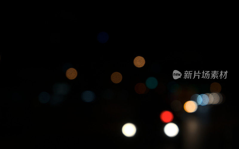 在城市漆黑的夜晚，车灯的彩色圆圈虚化。模糊的抽象纹理背景。