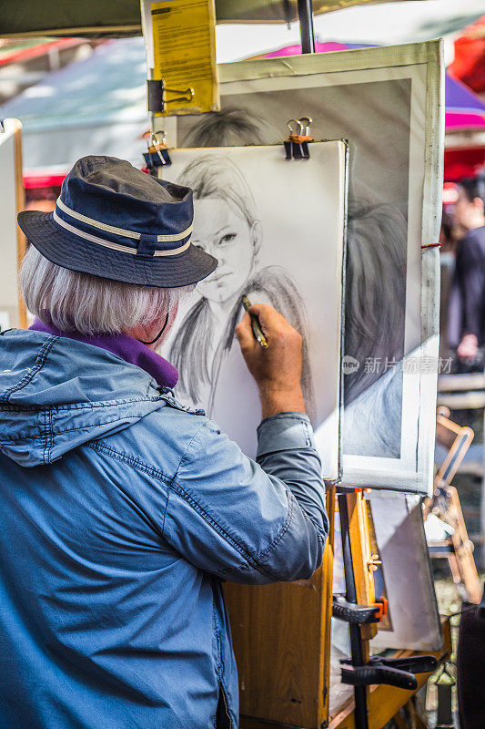 图为一名戴着帽子的绘图员在法国巴黎圣心大教堂附近的蒙马特广场