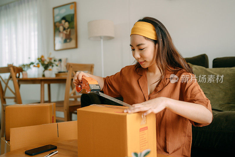 亚洲女人的主人包装纸板箱得到邮包。