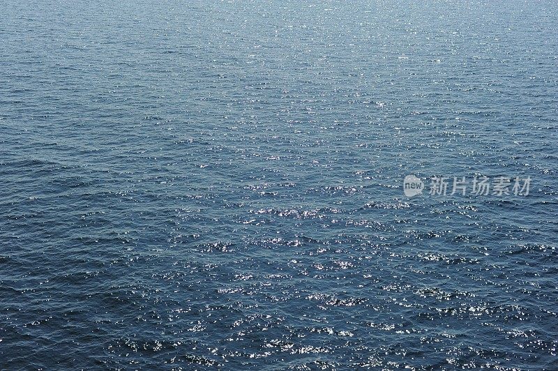 阳光下波光粼粼的蓝色海水和海水水面