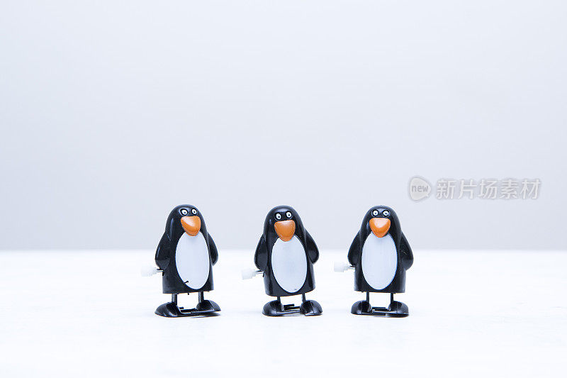 三个上发条的企鹅玩具排成一行，上面有复制空间