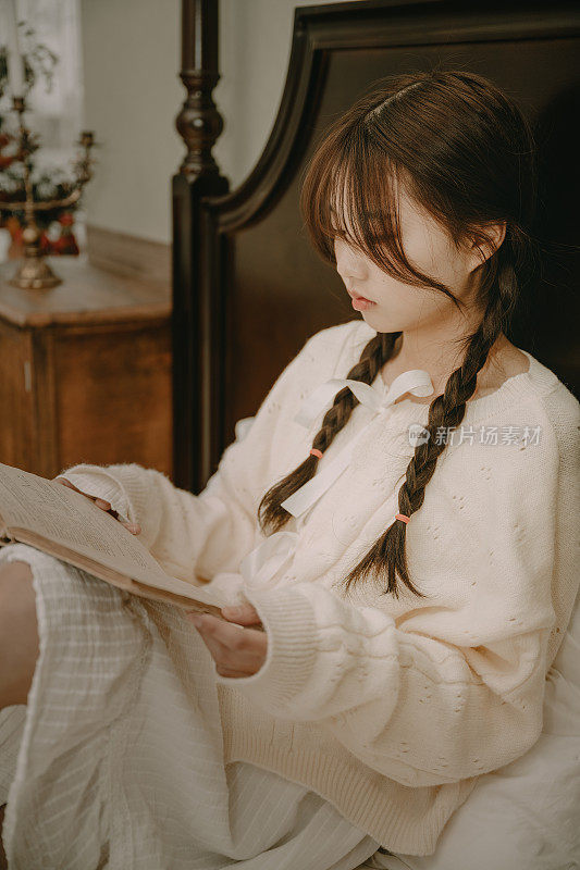 一个美丽的亚洲女孩在床上看书