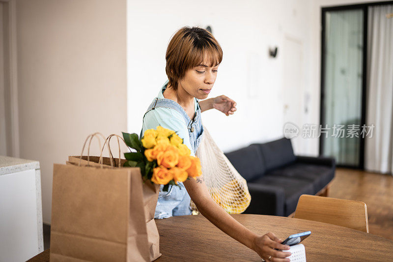 一个年轻的女人在家里整理杂货，用手机打电话