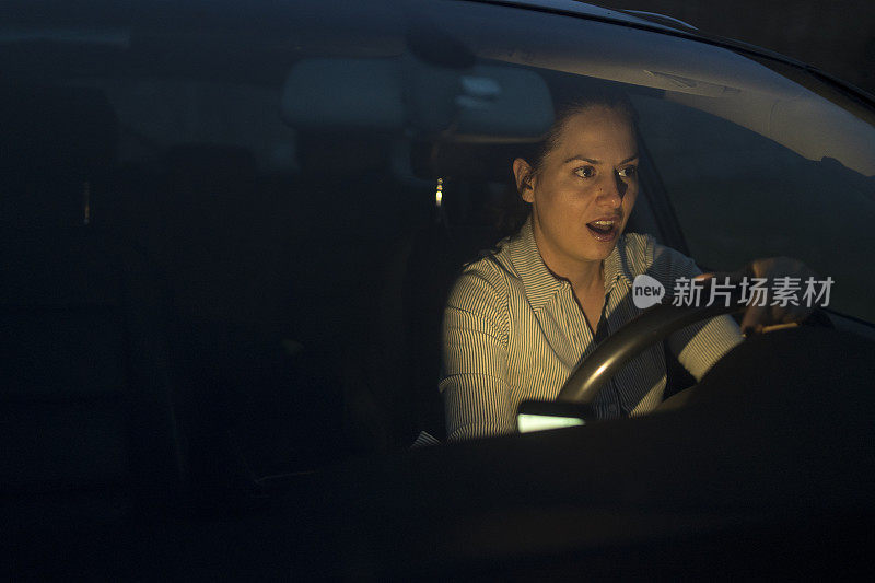 一名年轻女子一边开车一边用手机发短信，注意力不集中在路上