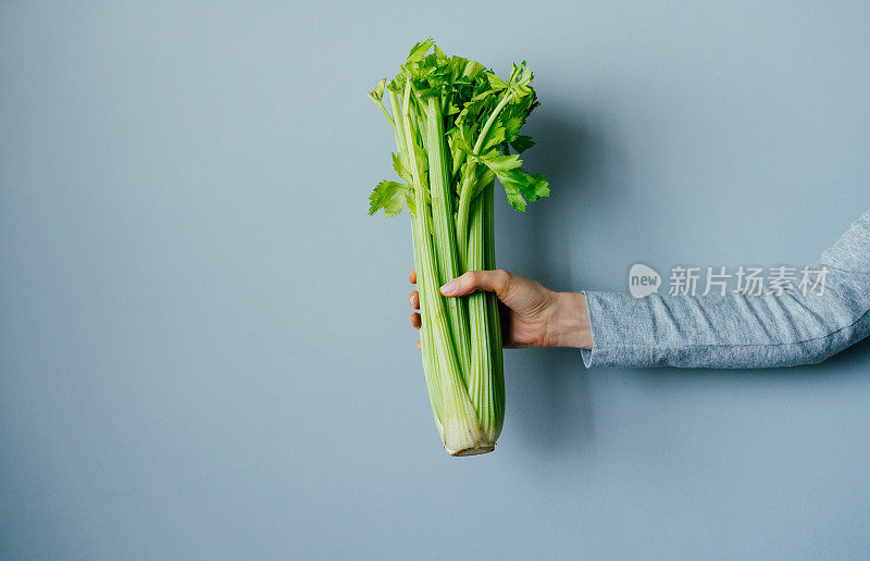 女人手握新鲜芹菜的特写照片