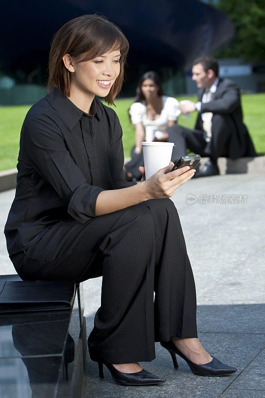 美丽年轻的华裔亚洲女人发短信和喝咖啡