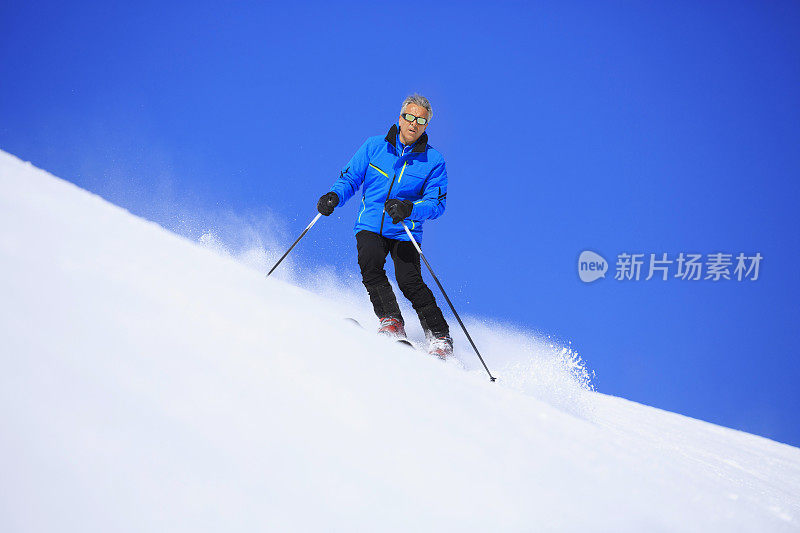 成熟的男人在阳光明媚的滑雪场滑雪