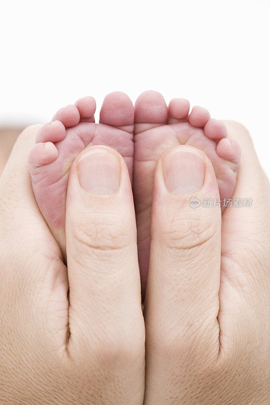 成人的手牵着婴儿的脚
