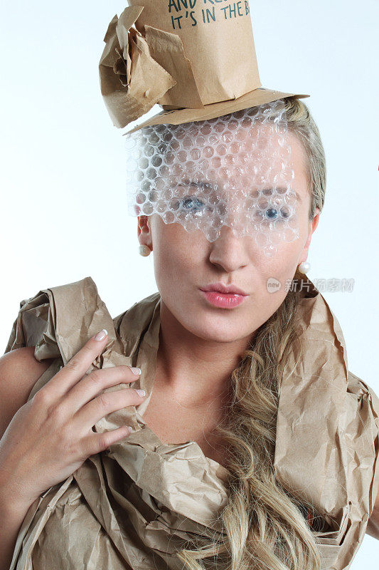 年轻女子戴着带面纱和围巾的回收纸帽子