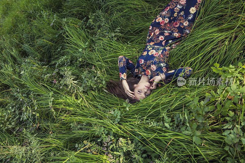 美丽的年轻女子穿着衣服躺在草地上