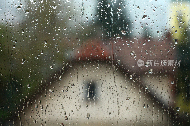 雨点落在窗户上，房子和教堂是背景