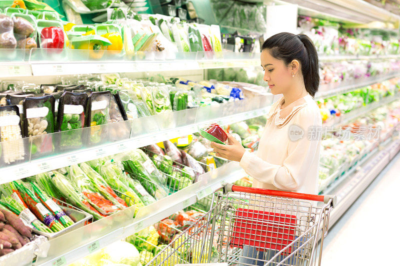 亚洲女人在商店里细心地考虑蔬菜