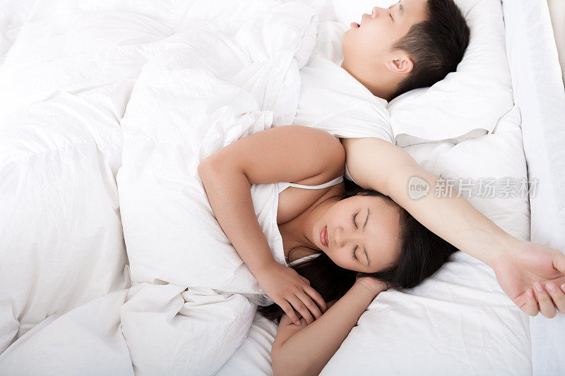 年轻的亚洲夫妇在床上睡觉