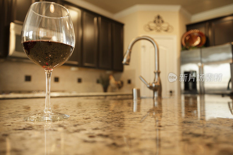 室内设计:在花岗岩家庭厨房柜台上放着一杯红酒