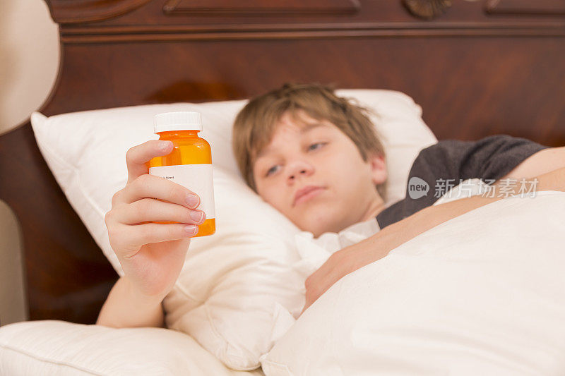 医疗保健:生病的青少年患流感卧床。药瓶子。